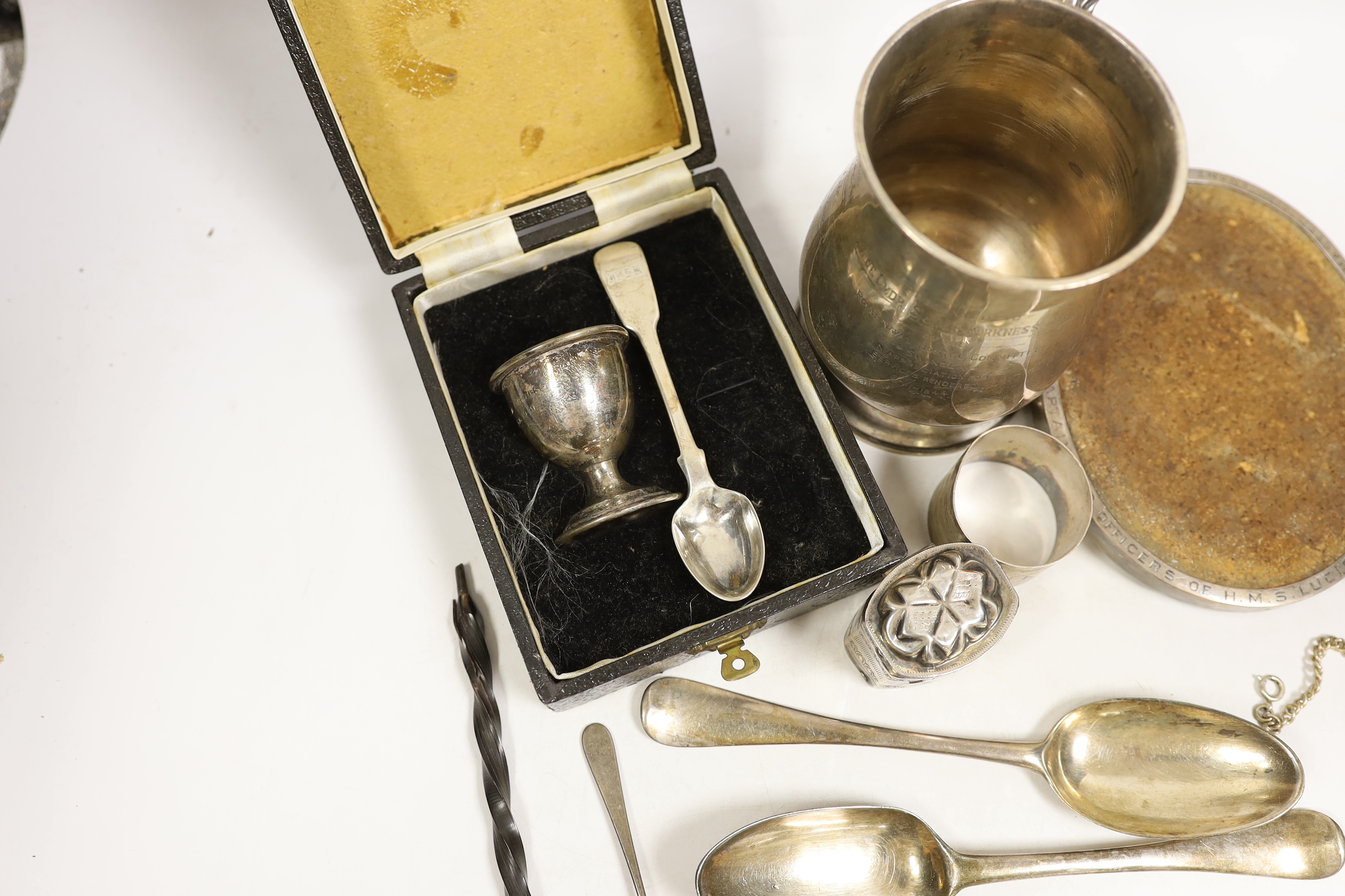 Assorted silver items including a silver mug engraved with signatures and inscription relating to Lieut. Commander S.J.M.P. Kirkness, R.N.R., London, 1942, 13cm, four 18th century base mark table spoons, a George IV cadd